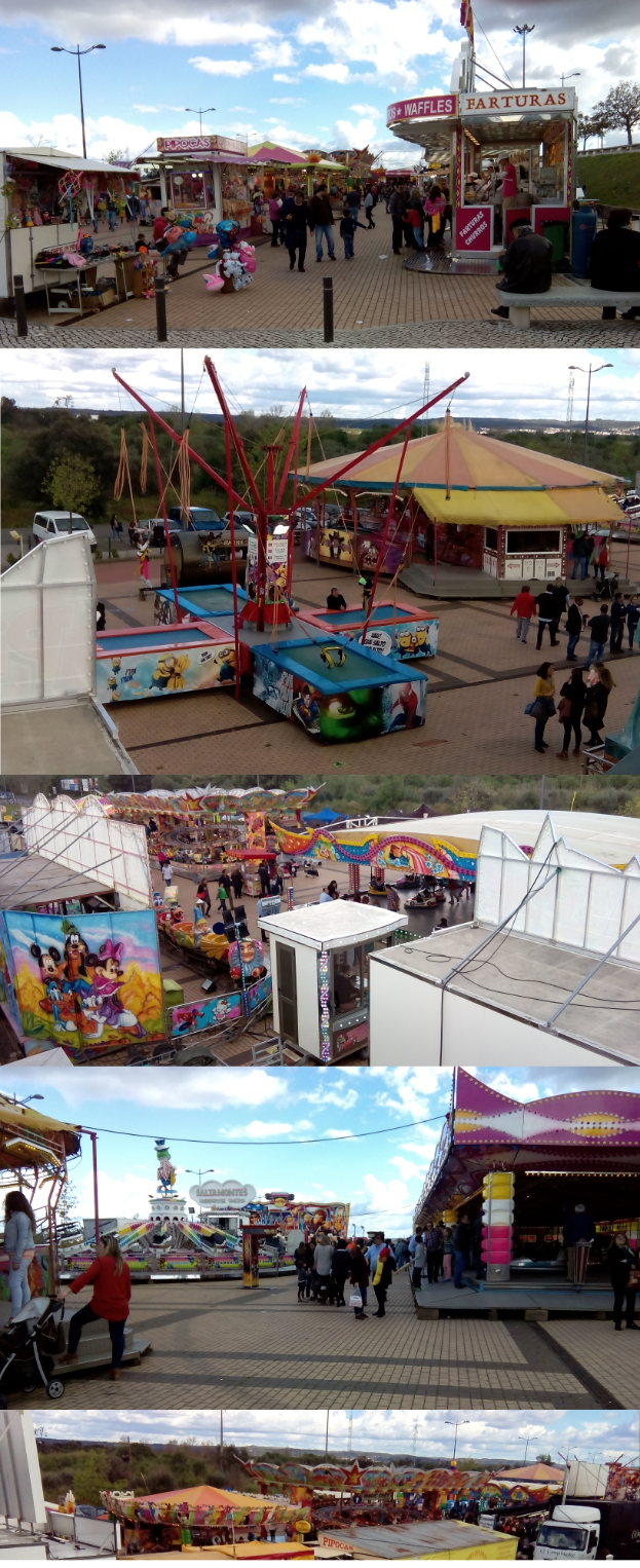 Eine Faschingszene mit Menschen, die herumstehen, umgeben von Buden, Fahrgeschäften, Pfählen, Lichtern, Bäumen und einem bewölkten Himmel.