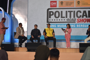 Eine Gruppe von Menschen auf einer Bühne mit einigen vor ihnen auf einem Podium stehenden und einem Schild im Hintergrund mit der Aufschrift "Cnn Political Road Show."
