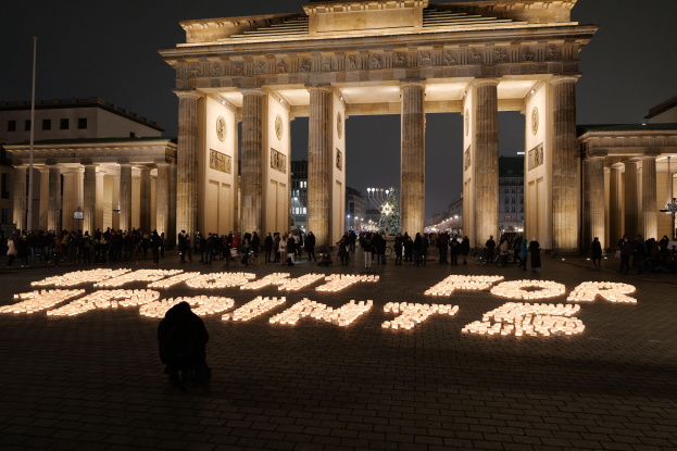 Menschen vor dem beleuchteten Reichstagsgebäude in Berlin, Deutschland mit 'Kampf für Freiheit' auf dem Boden.