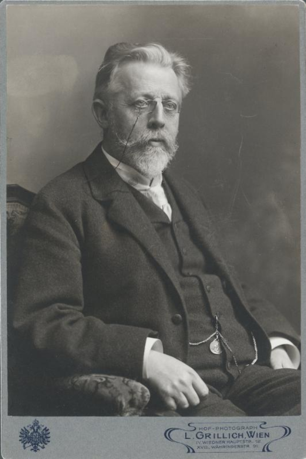 Schwarzes und weißes Porträt eines bärdigen Mannes mit Brille, der in einem Stuhl sitzt, beschriftet mit "L. Grillich Wien, der Gründer der deutschen Revolution."