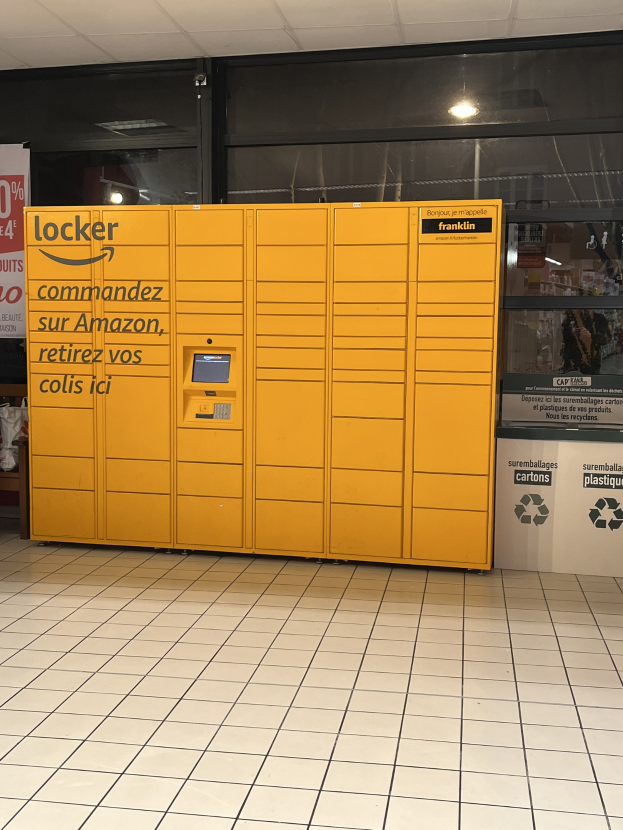 Ein gelber Spind mit Text darauf vor einer Glastür in einer U-Bahn-Station, umgeben von verstreuten Kartons und anderen Gegenständen, mit Stationwänden im Hintergrund.