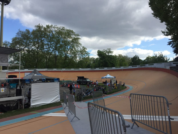 Gruppe von Radfahrern auf einer Schmutz BMX-Strecke bei den 2018 UCI BMX-Weltmeisterschaften, mit Zuschauern, Zelten und Fahrzeugen im Hintergrund.