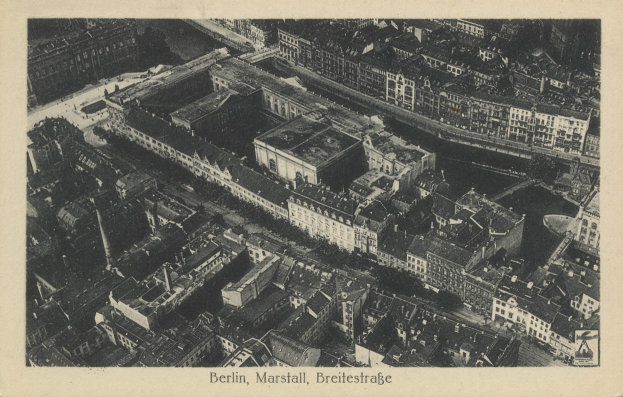 Schwarzes und weißes Luftbild einer dichten Stadtlandschaft mit einem zentralen Wolkenkratzer und Text unten.