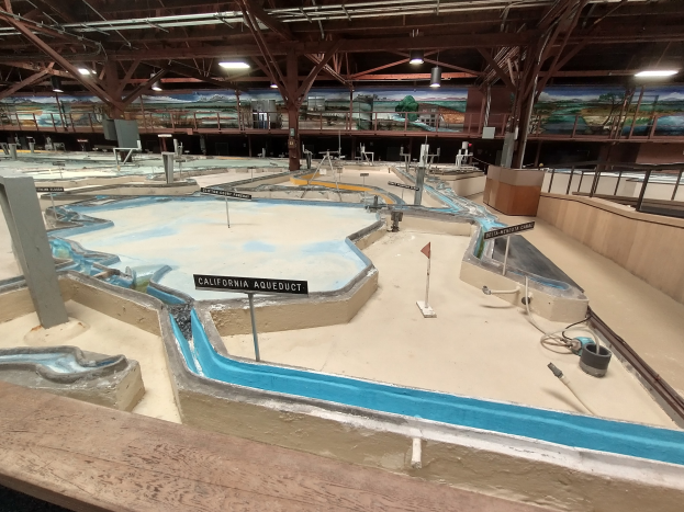 Großes Indoor-Wasserpark mit mehreren Wasserrutschen, Deckenbeleuchtung, Wandgemälden und Minigolfplatz.
