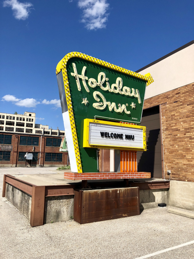 Holiday Inn-Schild an einem Gebäude mit einer Fußgängerdisplay und bewölktem Himmel.