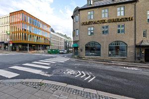 Das erste Hotel Breiseth in Berlin, Deutschland, mit Gebäuden mit Fenstern, Schildern mit Masten, Fahrzeugen auf der Straße und einem bewölkten Himmel im Hintergrund.