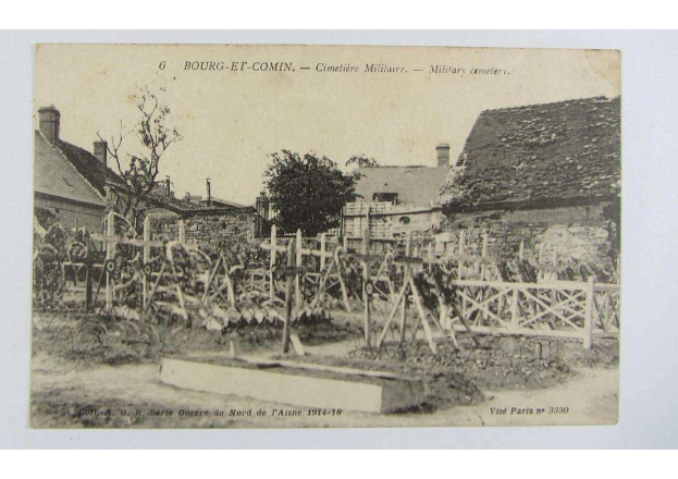 Altes Schwarz-Weiß-Foto eines Friedhofs in Bourg-et-Comin, Frankreich, das einen hölzernen Zaun, Bäume, Gebäude mit Fenstern und einen bewölkten Himmel zeigt, mit Text am unteren Rand.