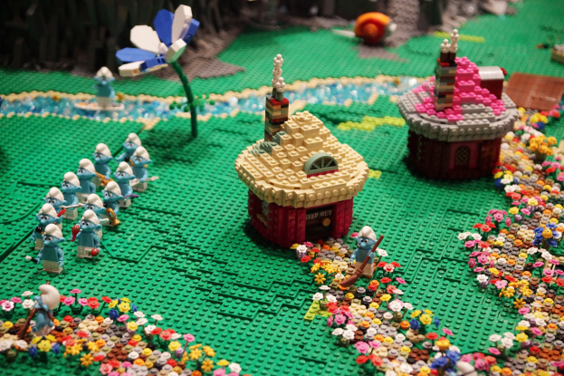 Ein Lego-Modell einer Kleinstadt mit Häusern, Blumen, Spielzeugen, Pflanzen und anderen Gegenständen auf einem leicht unscharfen, träumerischen Hintergrund.