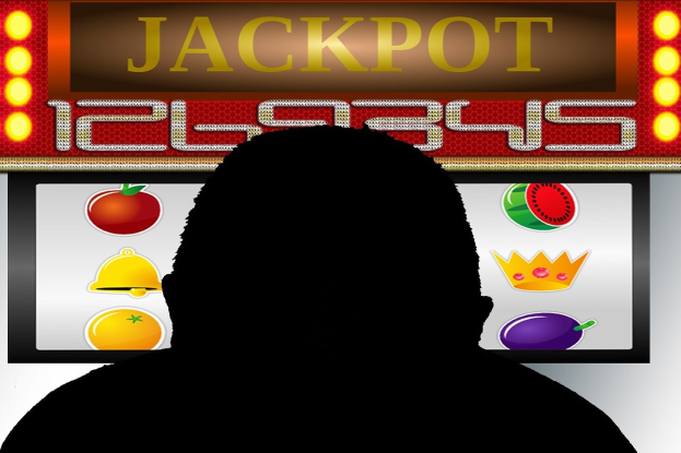 Mann spielt an einem Automaten mit "Jackpot"-Anzeige, umgeben von einer Tafel mit Text- und Obstbildern.