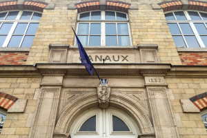 Ein mehrstöckiges Gebäude mit Glasfenstern und einer Tür, eine Flagge vorne und Text an der Fassade, der darauf hinweist, dass es ein Hotel ist.