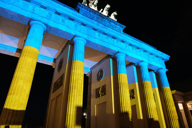 Das Brandenburger Tor in Berlin, Deutschland, erstrahlt in Blau und Gelb und präsentiert sich mit seinen Skulpturen gegen einen dunklen Hintergrund.