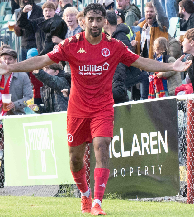 Ein Fußballspieler in roter Uniform rennt mit ausgebreiteten Armen auf einem Feld, im Hintergrund eine Menge und im Vordergrund ein Banner mit der Aufschrift "Middlesbrough FC v Swansea City - Sky Bet Championship".