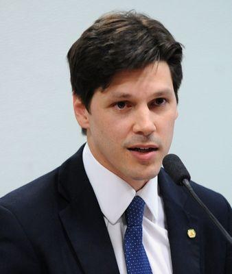 Ein Mann im Anzug und Krawatte spricht in ein Mikrofon an einem Rednerpult, wahrscheinlich um die Genehmigung eines Gesetzes zur Verbot des Internets durch die Regierung zu kommentieren.